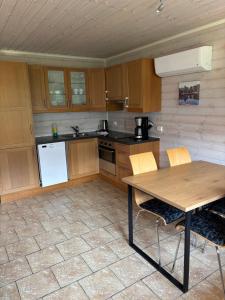 a kitchen with wooden cabinets and a table with chairs at Family Cabins in Fjæra