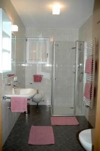 uma casa de banho com um lavatório e um chuveiro com tapetes cor-de-rosa em Residence Sonnberg em Perca