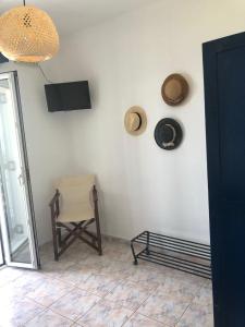 a room with a chair and a television on a wall at Meltemi Tinos in Agios Romanos