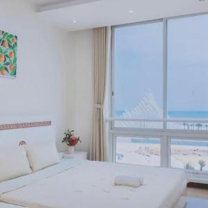 a bedroom with a white bed and a large window at Simpsons homestay - Oasky 36 #viewtamthang #viewbien #vungtau in Xã Thang Tam