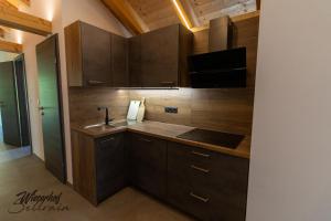 a kitchen with wooden cabinets and a sink at Wieserhof Sellrain in Sellrain +29 photos