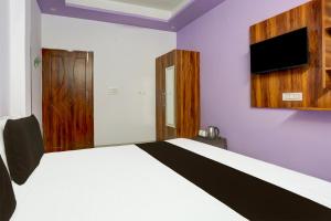 a bedroom with a bed and a tv on the wall at Hotel O Adinath Guest House in Bahādrābād