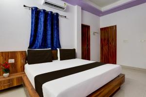 a bedroom with a large white bed with blue curtains at Hotel O Adinath Guest House in Bahādrābād