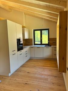 a large kitchen with white cabinets and a window at Ferienhof Haug in Bad Hindelang