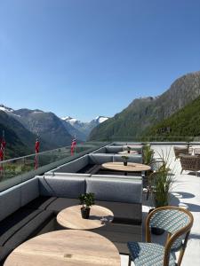 eine Terrasse mit Tischen und Stühlen und Bergen in der Unterkunft Hotel Videseter in Stryn