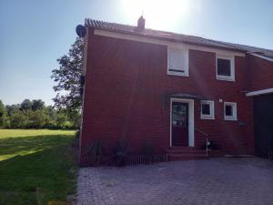 a red brick house with a door and a lawn at Ferienhaus Dat Landhuus 95158 in Rhauderfehn