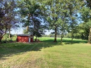 a red shed in a field with trees at Ferienhaus Dat Landhuus 95158 in Rhauderfehn