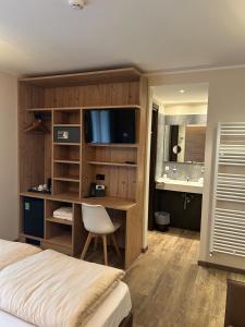 ein Schlafzimmer mit einem Bett und einem Schreibtisch mit Fernseher in der Unterkunft Hotel Le Cime in Val Masino