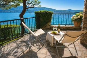 a table and chairs on a balcony with a view of the water at Villa Coccodrilla in Toscolano Maderno