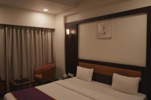 a hotel room with a bed and a chair at Hotel Rajhans Regent in Bhopal +41 photos