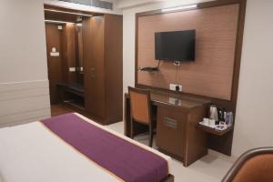 a hotel room with a bed and a desk and a tv at Hotel Rajhans Regent in Bhopal