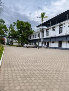 a parking lot in front of a building with palm trees at PRATHIBA RESIDENCY in Kollam