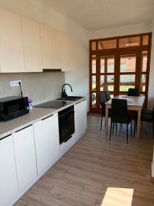 a kitchen with white cabinets and a table with chairs at WINE NOT Tállya in Tállya