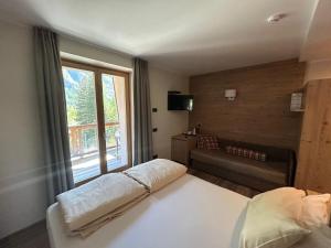 ein Schlafzimmer mit Bett, Fenster und Sofa in der Unterkunft Hotel Le Cime in Val Masino