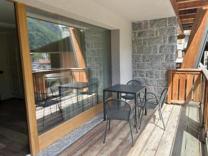 eine Terrasse mit Tisch und Stühlen auf einem Deck in der Unterkunft Hotel Le Cime in Val Masino