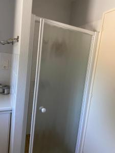 a shower with a glass door in a bathroom at Meublé BLEU in Réaumur