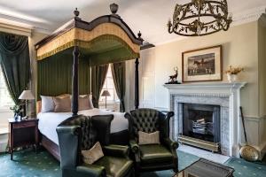 a bedroom with a canopy bed and a fireplace at Chilston Park Hotel in Maidstone
