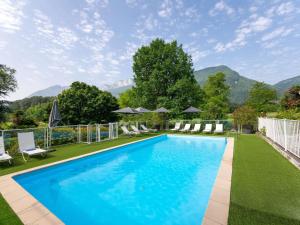 a swimming pool with chairs and mountains in the background at Novotel Grenoble Nord Voreppe in Voreppe