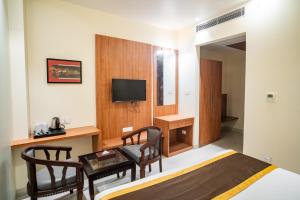 a room with a bed and a table and a television at Hotel Avenue 30 in Lucknow