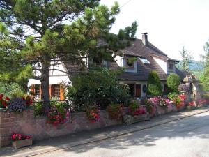 a house with flowers in front of a stone wall at Le Sonnenglanz in Beblenheim