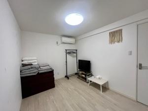 a white room with a mirror and a tv at Guest House TETSU in Oshima