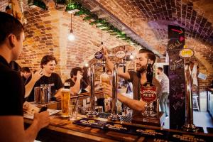 a man standing at a bar making a drink at Wombat's City Hostel London in London +58 photos