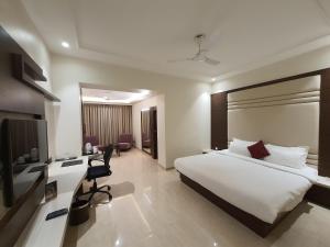 a hotel room with a large bed and a desk at Grand Heritage Narmada Jacksons in Jabalpur