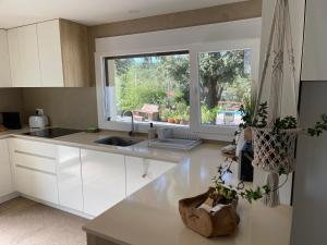 a kitchen with white cabinets and a large window at Casa das Cucas in Pombal
