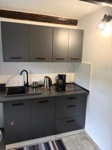 a kitchen with black and white cabinets and a sink at Cozy Forest House in Jonkowo