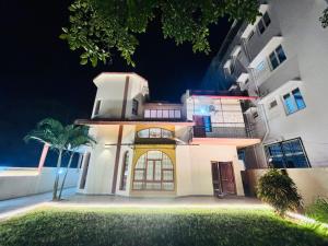 a white house with a palm tree in front of it at Majestic Villa, 5 Bedroom AC in Mysore in Mysore