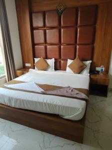 a bedroom with a large bed with a wooden headboard at Hotel Shree Amrit Ganga in Haridwār +1 photo