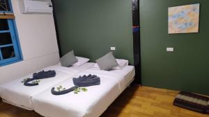 two twin beds in a room with green walls at Laena Homestay in Ko Yao Noi +5 photos