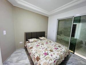 a bedroom with a bed and a large window at Ninou diamants in Harqalah