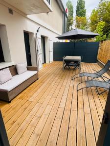 a patio with a couch and a table and an umbrella at L'Apparté Confort in Thonon-les-Bains