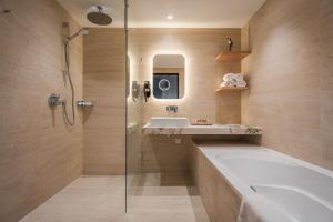 a bathroom with a tub and a sink and a shower at Van der Valk Hotel Emmen in Nieuw-Amsterdam