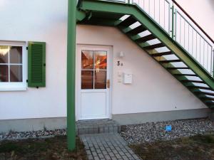 eine Treppe, die zu einer weißen Tür mit einer grünen Schiene führt in der Unterkunft Ferienwohnung Usedomresidenz in Ostseebad Karlshagen