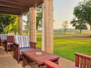 a patio with a table and chairs and a view of a field at Centurion Golf Suites Boca Walk in Centurion