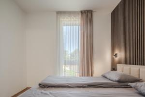 a bedroom with a bed and a large window at TOPOLIŲ Apartamentai in Palanga