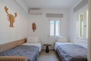 two beds in a room with two windows at Kriolithos Houses in Parikia
