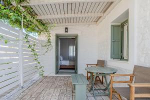 a patio with a table and benches and a door at Kriolithos Houses in Parikia