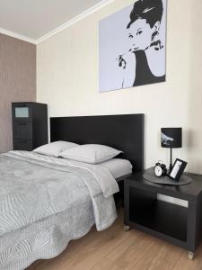 a bedroom with a bed and a table with a lamp at Vienibas apartment in Daugavpils