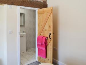 a bathroom with a wooden door and pink towels at Christine Cottage in Flamborough