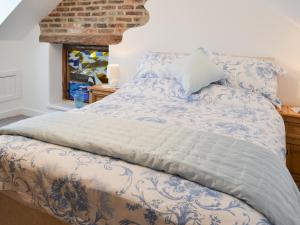 a bed with a blue and white comforter and a window at Christine Cottage in Flamborough +11 photos