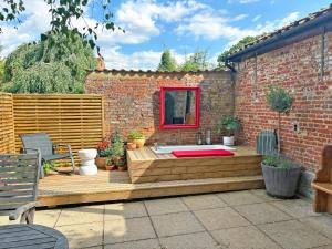 a wooden deck with a hot tub in front of a brick building at Sparrows Nest - Uk50109 in Longham