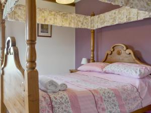 a bedroom with a canopy bed with pink walls at Riverview - Ioj in Brandesburton +11 photos