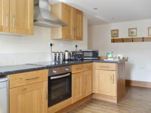 a kitchen with wooden cabinets and a microwave at Broad Leaf - Iok in Brandesburton
