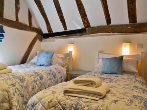 two twin beds in a room with beams at Walnut Cottage in Sproughton