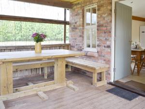 a patio with a wooden table and a bench at Four Bays - Ioh in Brandesburton