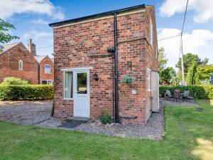a brick house with a white door and a yard at Edlington Hall Cottage in Edlington