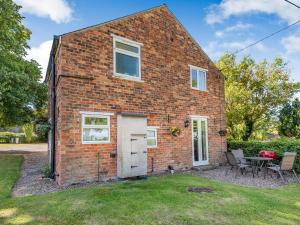 a brick house with a white door and a table at Edlington Hall Cottage in Edlington